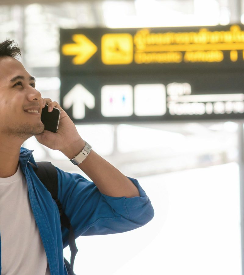 Asian traveler using the smart mobile phone and calling at modern an airport,